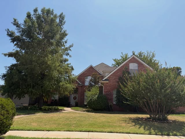 Two-story brick home with mature trees, recent project